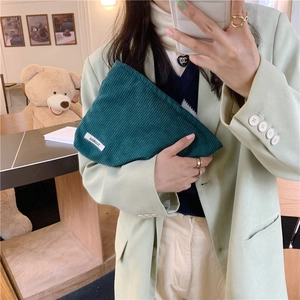 Detail of dark green corduroy handbag showing soft texture and premium side woven label