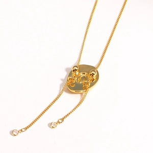 Close-up of golden necklace featuring a diamond-set lariat slide and quilted texture detail