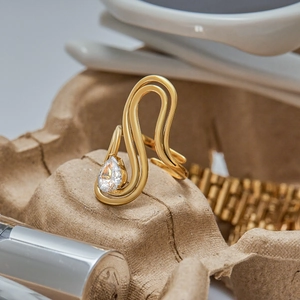 Detail of 18K gold stainless steel wavy ring with teardrop zircon on natural fiber