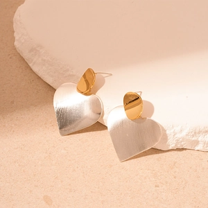Detail of heart earrings showing gold and silver mixed metal with brushed texture
