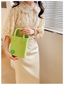 Detailaufnahme der grasgrünen EVA Jelly-Tasche mit Sonnenblumen-Anstecker bei natürlichem Licht