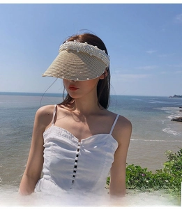 Detail of handmade straw visor with faux pearls on the brim for beach sun protection