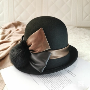 Detail of black wool felt cloche hat with bronze satin bow and faux fur pompom detail