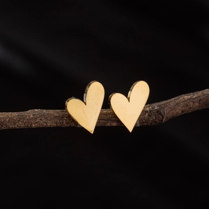 Boucles d'oreilles cœur dorées irrégulières présentées sur une branche naturelle