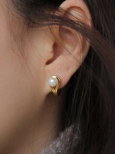Elegant gold drop earrings with a natural white pearl accent worn by a model