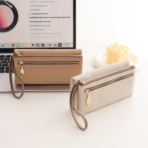 Detail of dual-zipper wallets with leaf-shaped metal pendants and wrist strap handles