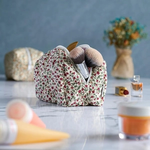 Floral makeup bag on a marble surface with blurred cosmetics and perfume bottles
