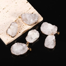 Detail of six raw white druzy quartz pendants with gold-plated edges on marble