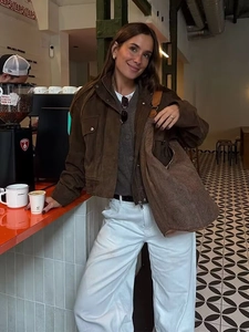 Close-up of brown faux suede jacket styled with a paisley crossbody bag in a cafe setting
