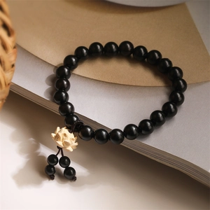 Macro detail of black sandalwood prayer beads with a white lotus charm on a book