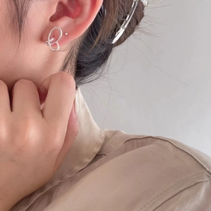 Macro view of sterling silver woven stud earrings worn on a model's earlobe