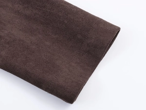 Detail of dark brown faux suede fabric with precise stitching on sleeve and hem