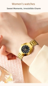 Detail of gold quartz watch with black dial, crystal indices and date display on a wrist