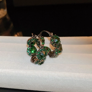 Macro shot of vintage luxury green gemstone hoop earrings with sparkling diamond accents