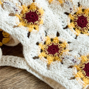 Detailed close-up of handmade crochet sunflower knit pattern on a beige fabric
