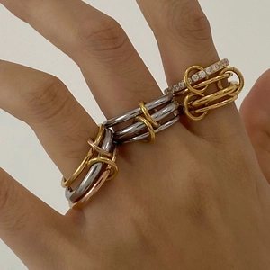 Detail of stacked tricolor interlocking bands with a gold-paved crystal ring on finger