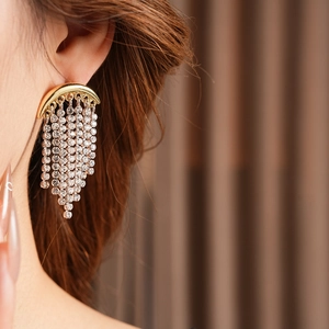 Close-up of elegant gold moon tassel earrings with sparkling rhinestones on a female model