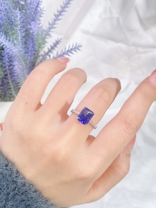 Macro view of an S925 silver ring featuring a blue rectangular cut stone on a finger