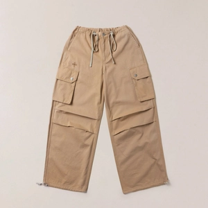 Detail of khaki wide-leg cargo pants featuring adjustable drawstring cuffs and cross embroidery
