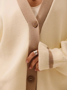 Detail of knit cardigan with V-neck, buttons, and contrast cuffs in beige and brown