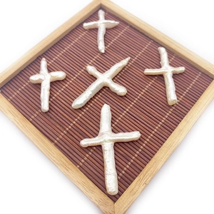 Natural white freshwater baroque cross pearls displayed on a bamboo tray background