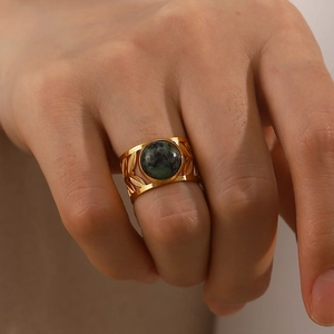 Detailed view of an 18K gold-plated steel ring with leaf patterns and green turquoise