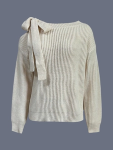 Dettaglio maglione in maglia crema con trama a costine e grande fiocco decorativo sulla spalla