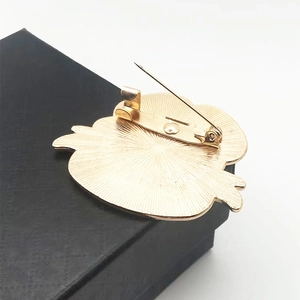 Vue arrière de la broche coquelicot dorée avec épingle sur une boîte cadeau noire