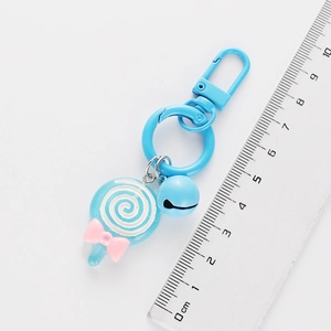 Blue lollipop keychain with pink bow and small bell on a white background with ruler