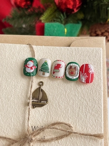 Christmas nail art decals with reindeer and tree designs on textured beige cardstock