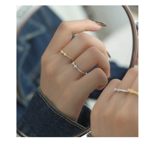 Close-up of bow ring with cubic zirconia on mirror surface, showing gold and silver finish