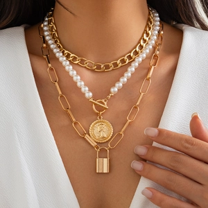 Detailed view of layered golden necklaces featuring baroque pearls and coin pendants