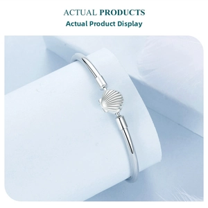Detail of s925 sterling silver bangle featuring a polished shell motif and ribbed texture
