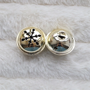 Detail of golden metal bells with snowflake, star and moon cutouts on white fur