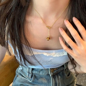 Golden Saturn necklace with zircon and tiger eye stone pendant on female model