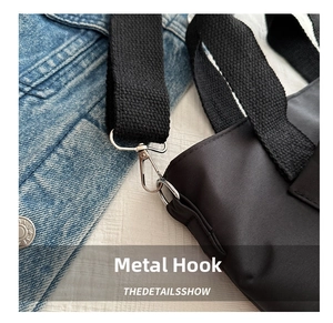 Detalle de gancho de metal plateado y correa tejida extraíble en un bolso negro
