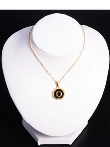 Macro view of 18K gold stainless steel necklace with round black enamel letter O pendant