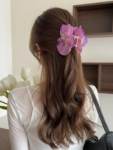 Detail of a purple orchid hair claw clip with silk petals and a pearl in a half-up hairstyle
