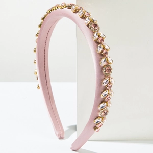 Detailed view of pink satin padded headband with shimmering rhinestones on white display