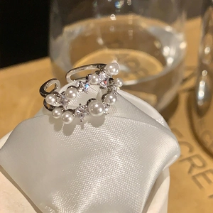 Dettaglio macro dell'anello a doppio strato con perle e strass a stella su raso bianco