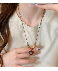 Macro shot of bohemian necklace with heart pendant, wood beads, and Saturn ring emblem