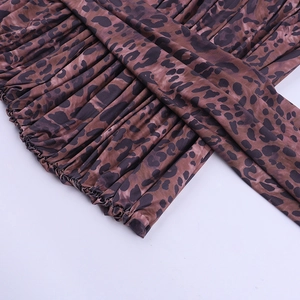 Detail of leopard print mini dress featuring elastic ruffled hem and brown animal pattern