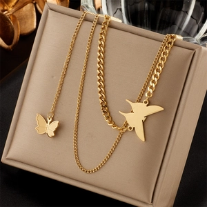 Detail of gold layered necklace with butterfly and bird pendants on cuban chain