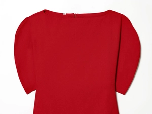 Détail d'un haut rouge à col bateau avec manches bouffantes et texture lisse de qualité