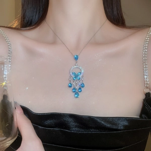 Close-up of elegant silver necklace with blue teardrop zircon and butterfly pendant