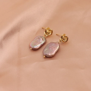 Detailed close-up of golden rose-shaped stud earrings with baroque lavender pearls