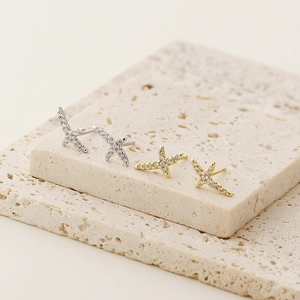 Detail of silver and gold cross star stud earrings with crystals on stone blocks