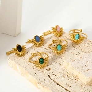 Set of six 18k gold plated sunburst rings with colorful oval gemstones on a stone plate