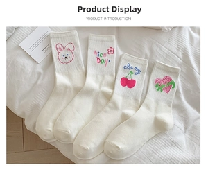 Detail of white cotton socks with pink rabbit and cherry embroidery on ribbed cuffs