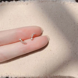 Minimalist sterling silver wheat spike stud earrings with tiny diamonds held on fingertips